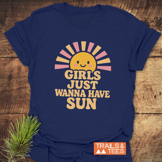 Girls Want Fun T-Shirt with a smiling sun and retro text, laid on wood. Made from soft, durable cotton by Trails & Tees.