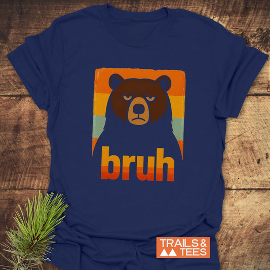 Navy BRUH Bear Funny T-Shirt with a grumpy bear and retro stripes, featuring durable prints and outdoor-themed design, laid on a wooden surface.