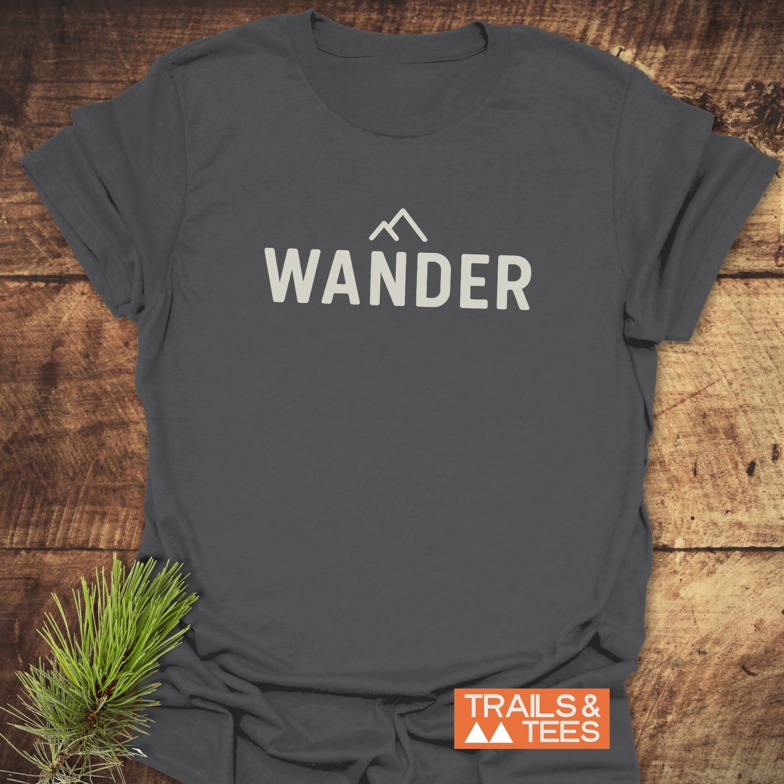 Heather-gray 547 Wander Minimalist T-Shirt with bold WANDER text and mountain icon. Includes TRAILS & TEES badge; designed for everyday outdoor adventures.