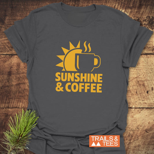 Bold Sunshine & Coffee T-Shirt featuring a yellow sun-coffee graphic and “SUNSHINE & COFFEE” text, laid flat with Trails & Tees logo visible.