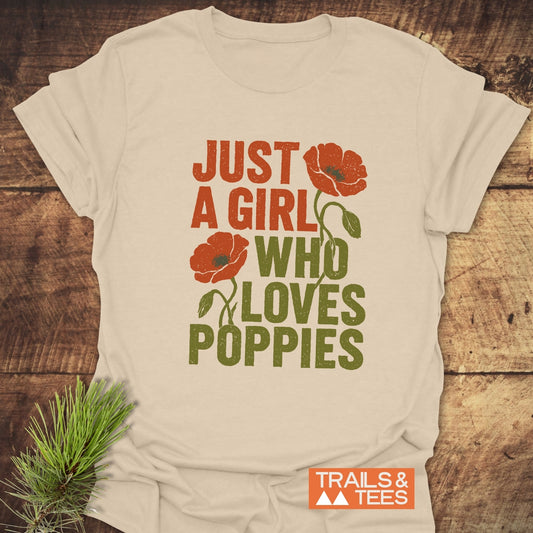 Grunge Poppy Love T-Shirt with orange poppy graphic and slogan, laid on wood, next to pine sprig; features durable, soft ring-spun cotton, pre-shrunk for fit.