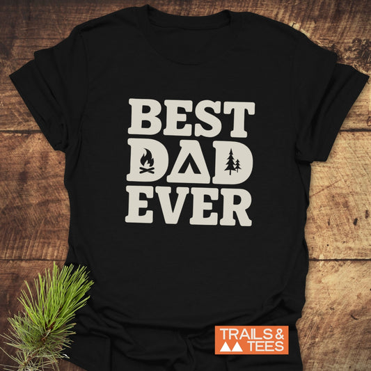Best Dad Ever Camping T-Shirt featuring outdoor-themed lettering, laid on wood. Made from soft cotton, pre-shrunk for fit, with durable prints.