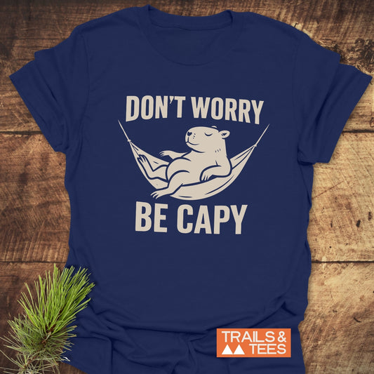 Don't Worry Capybara T-Shirt featuring a cream graphic of a capybara in a hammock, with a slogan, on soft, durable cotton.