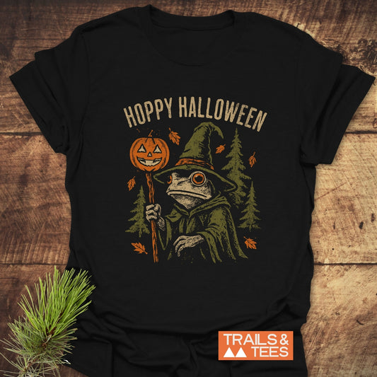 Hoppy Halloween T-Shirt with a wizard toad, jack-o’-lantern staff, autumn leaves, evergreen trees; soft cotton, durable print, taped shoulders for lasting fit.