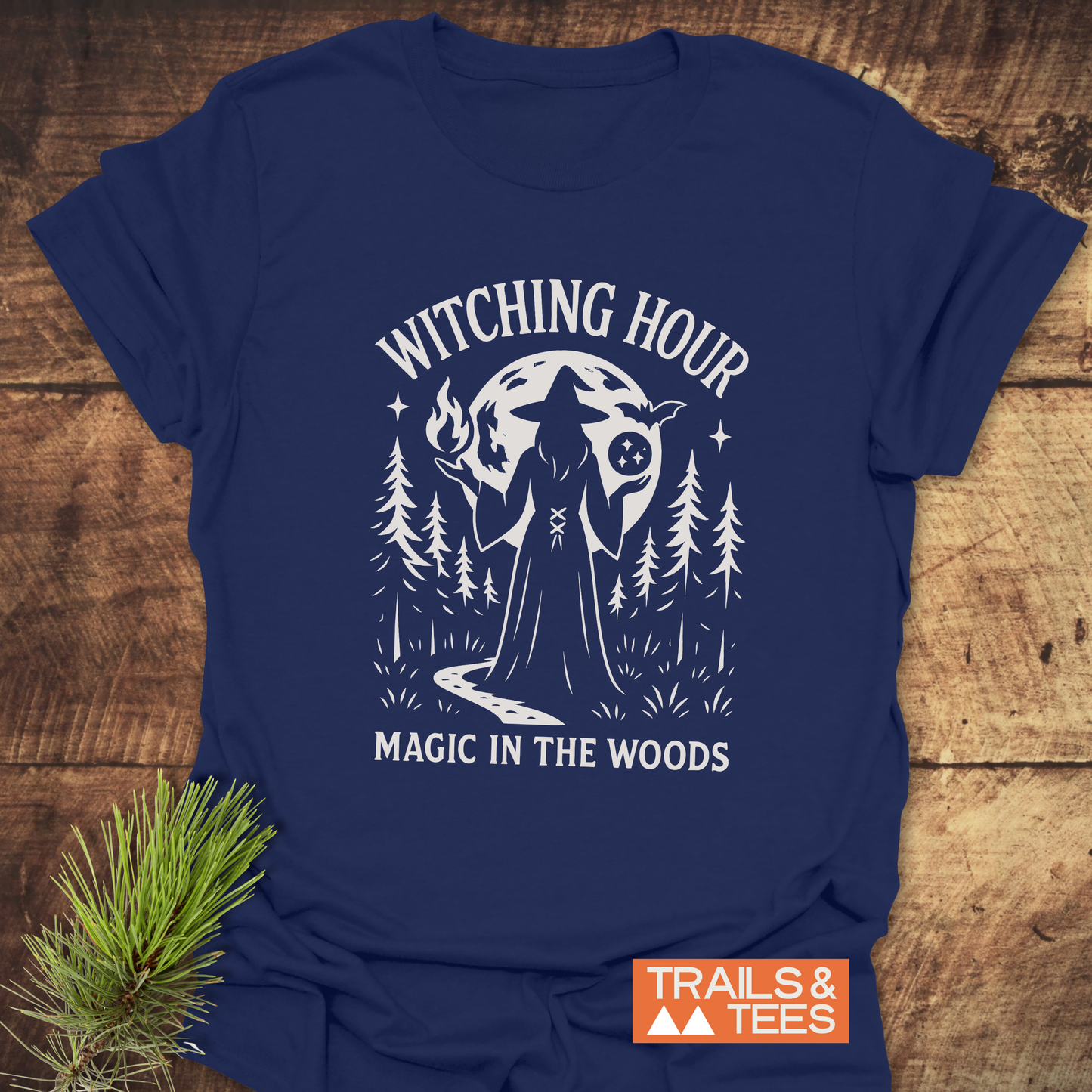 Witching Hour T-Shirt featuring a white witch graphic amidst pine trees and moon, crafted from soft ring-spun cotton for comfort and durability.