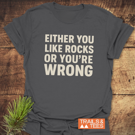 Heather-gray Either You Like Rocks T-Shirt on rustic surface, with off-white block letters. Features soft, lightweight cotton for outdoor enthusiasts. Logo: TRAILS & TEES.