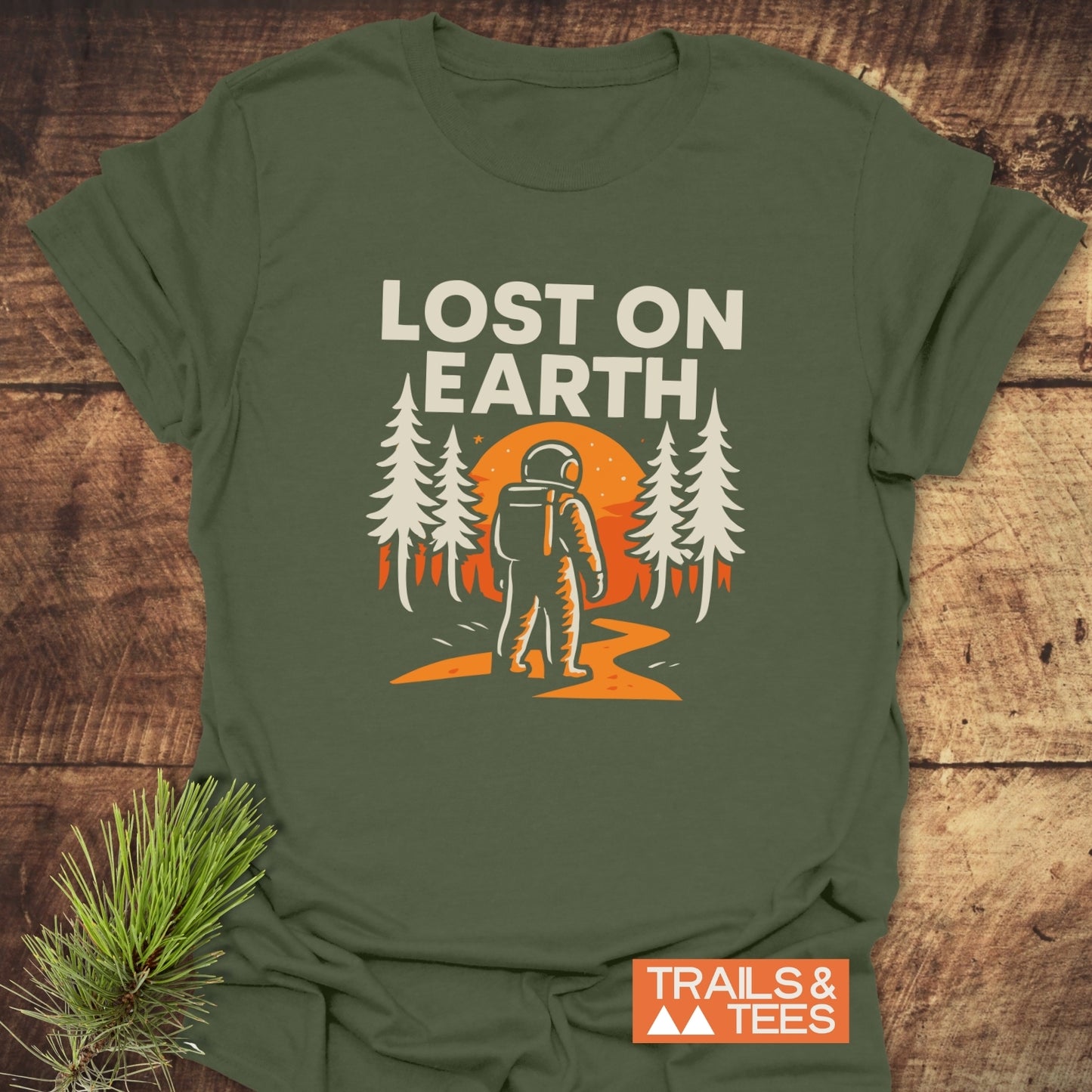 Lost On Earth T-Shirt featuring an astronaut graphic and slogan, crafted from soft cotton for comfort, ideal for outdoor enthusiasts. Brand logo: TRAILS & TEES.