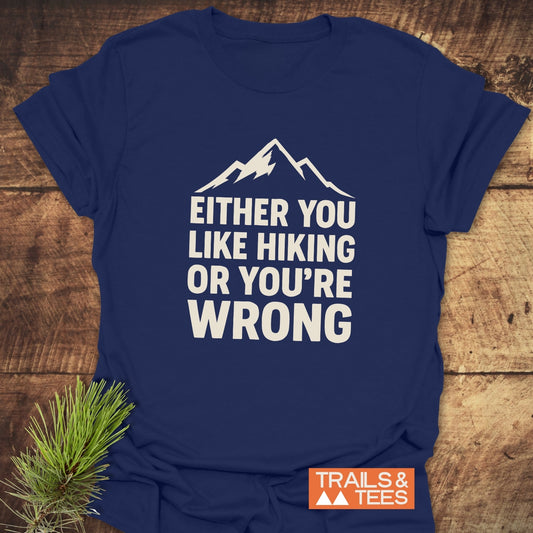 Navy-blue Either You Like Hiking T-Shirt with mountain graphic and bold text, showcasing outdoor spirit. Laid flat with pine sprig, featuring durable, eco-friendly design.