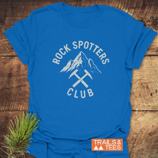 Rock Spotters Club T-Shirt featuring a mountain graphic with ice axes, styled for outdoor enthusiasts. Crafted from soft cotton, ensuring comfort and durability.