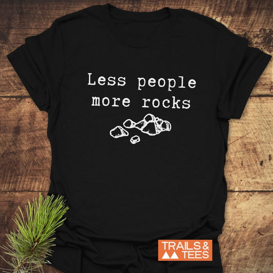 Less People More Rocks T-Shirt on wood, featuring white text and rock illustration. Soft, ring-spun cotton for adventures. Includes TRAILS & TEES logo.