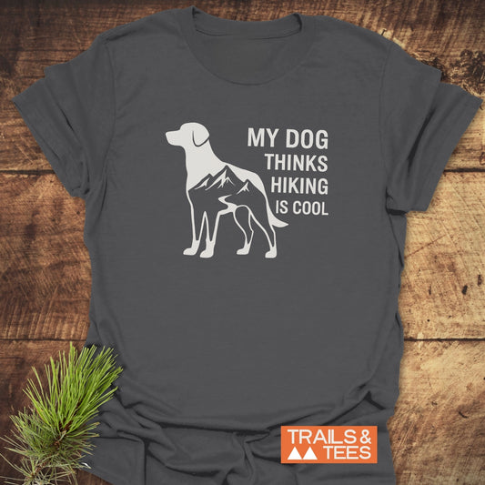 Dog Thinks... T-Shirt: Dark-gray tee with a white dog silhouette filled with mountains, MY DOG THINKS HIKING IS COOL text, and TRAILS & TEES logo.