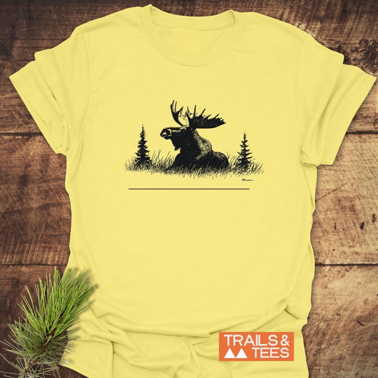 Relaxing Moose T-Shirt featuring a black moose silhouette with saplings on pale yellow fabric, showcasing durable DTF prints, perfect for outdoor enthusiasts.