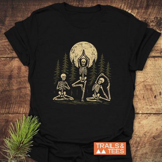 Relax In The Woods T-Shirt featuring skeletons in yoga poses with pine trees and a full moon; crafted from soft, lightweight cotton for trail-tested comfort.