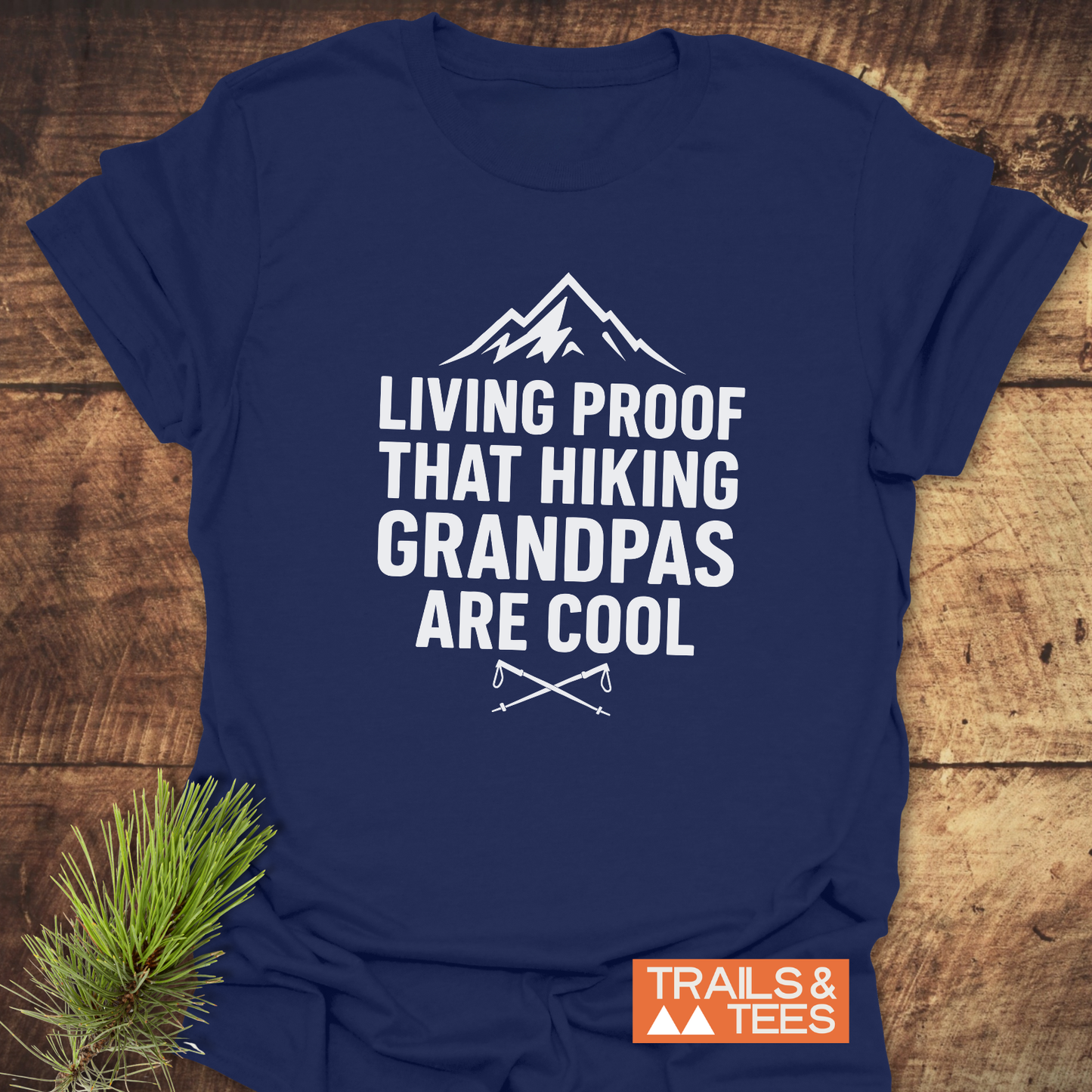 606 Living Proof Grandpa T-Shirt featuring a mountain graphic and hiking slogan, laid on rustic wood. Includes durable design details for outdoor enthusiasts.