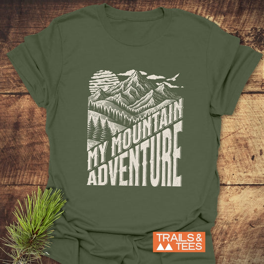 Forest-green T-shirt featuring a distressed white graphic of mountains and trees with MY MOUNTAIN ADVENTURE text, highlighting outdoor exploration spirit.