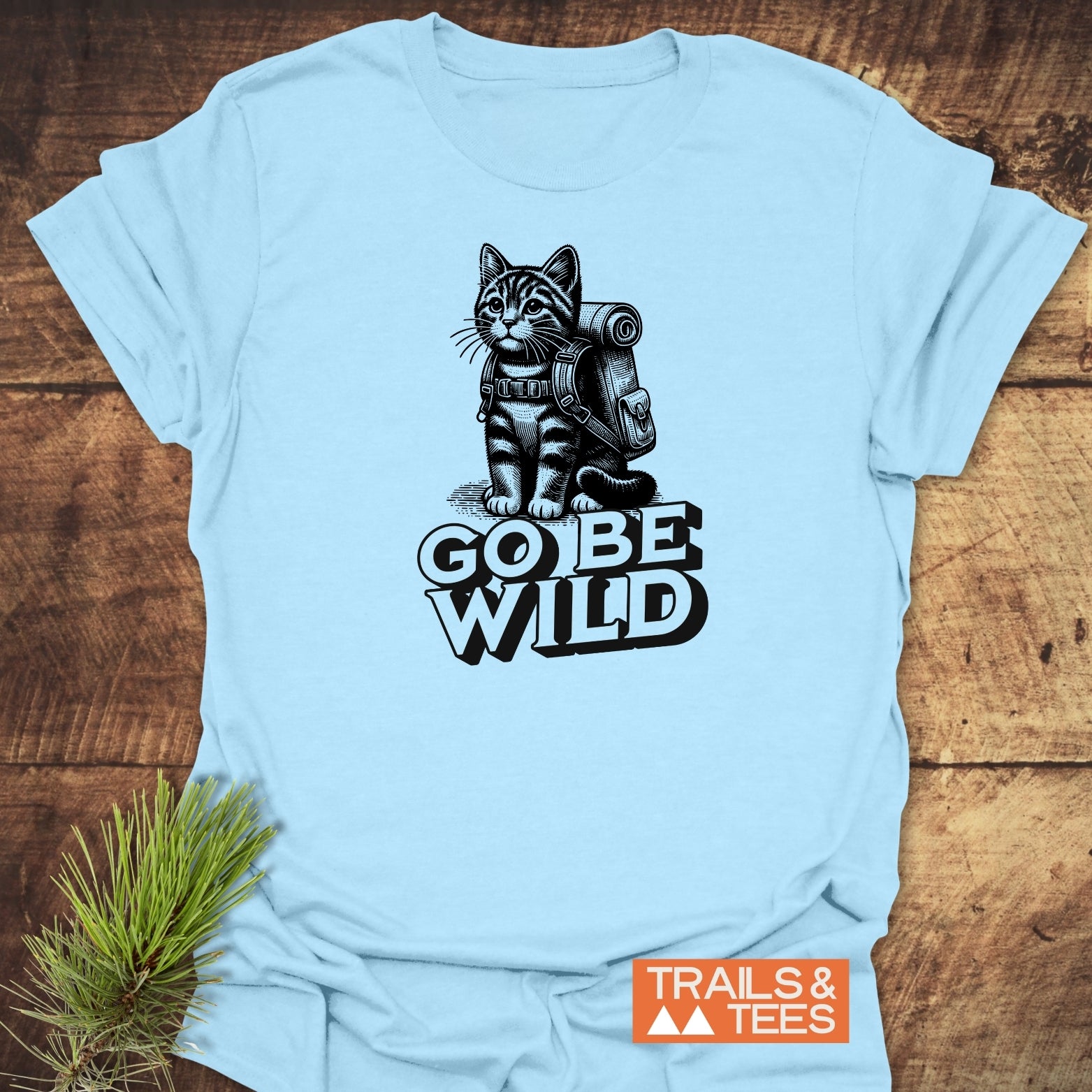 Light-blue Go Be Wild Cat T-Shirt with kitten illustration and slogan, features durable print on soft cotton, designed for outdoor enthusiasts by Trails & Tees.