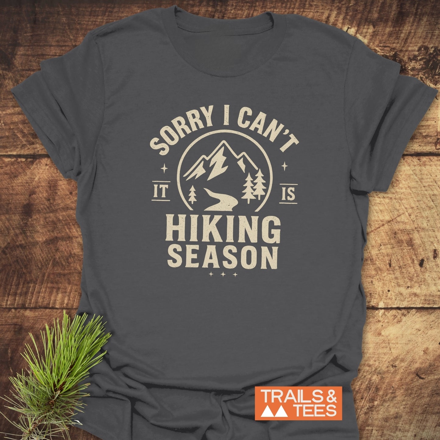 Charcoal-gray 620 Hiking Season T-Shirt featuring a mountain graphic and hiking season slogan, emphasizing comfort and adventure. Includes small orange TRAILS & TEES logo.