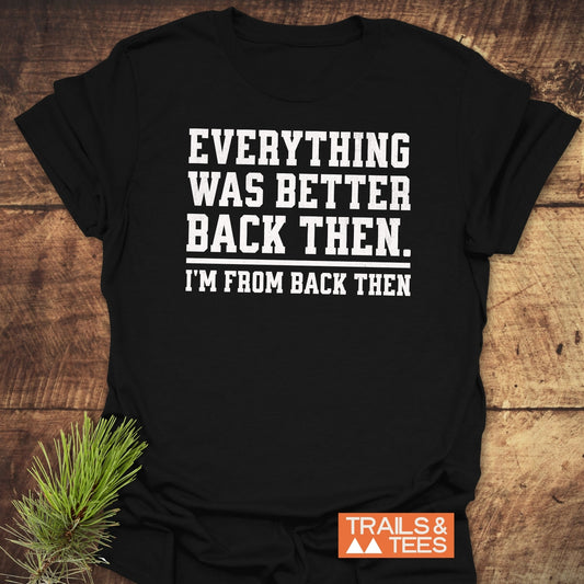 Back Then Funny T-Shirt on wood, features bold white slogan, “EVERYTHING WAS BETTER BACK THEN. —I’M FROM BACK THEN—”, with “TRAILS & TEES.” logo nearby.