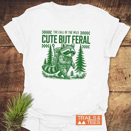 Cute But Feral T-Shirt featuring a raccoon hiking design, crafted from soft ring-spun cotton, with durable prints and pre-shrunk for lasting comfort.