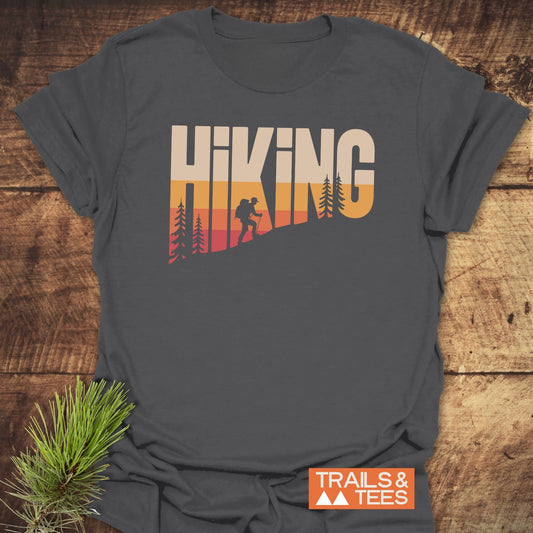 Hiking Vintage T-Shirt featuring HIKING sunset gradient graphic with pine tree silhouettes, crafted from soft cotton for comfort and durability, ideal for outdoor enthusiasts.