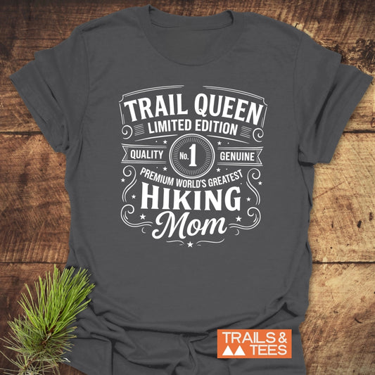 Charcoal-gray T-shirt with Trail Queen – Limited Edition white vintage design, beside pine sprig, highlighting comfort and durable quality for outdoor-loving moms.