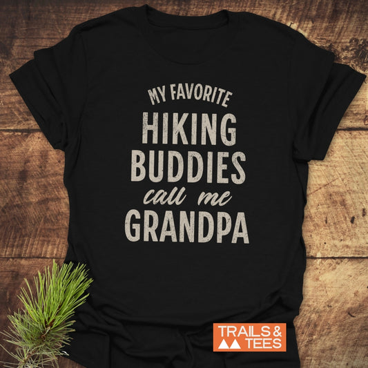 Black Hiking Grandpa T-Shirt with off-white slogan, crafted from soft cotton, featuring durable prints and taped shoulders for comfort. Displayed on wooden surface with pine sprig.