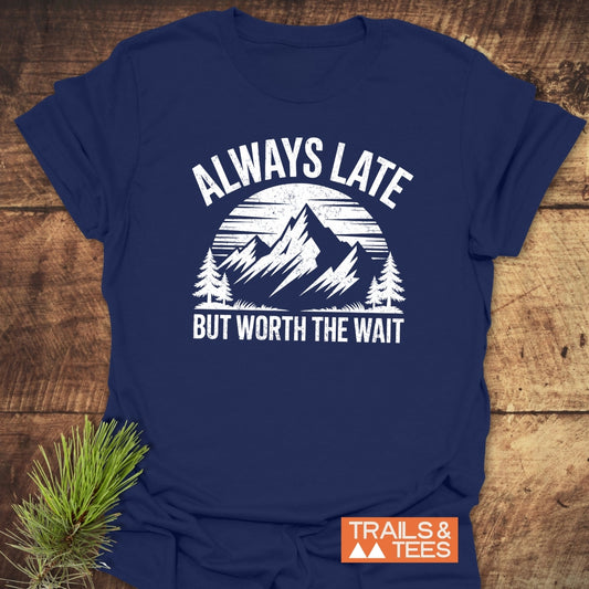 Navy T-shirt with mountain scene and ALWAYS LATE BUT WORTH THE WAIT slogan. Features durable print, taped shoulders, and is pre-shrunk.