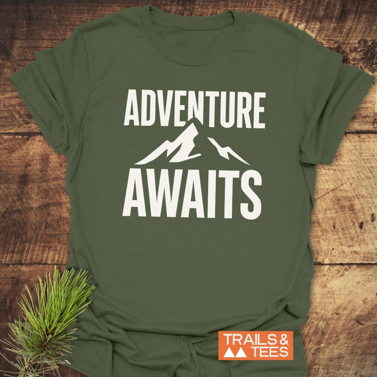 Adventure Awaits T-Shirt in forest-green with bold white text and mountain silhouette, made from soft cotton, featuring durable prints and sustainable production.
