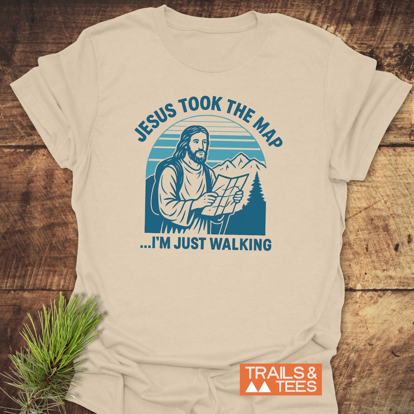 Jesus Took The Map T-Shirt featuring Jesus in hiking gear with a map, set against mountains. Made from soft, durable cotton for outdoor enthusiasts.