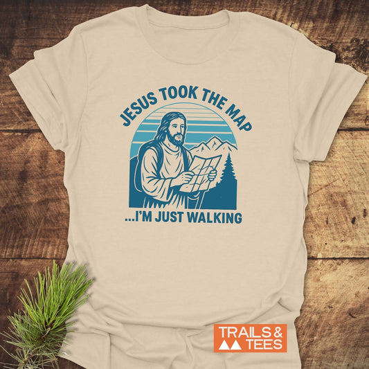 Jesus Took The Map T-Shirt featuring Jesus in hiking gear with a map, set against mountains. Made from soft, durable cotton for outdoor enthusiasts.