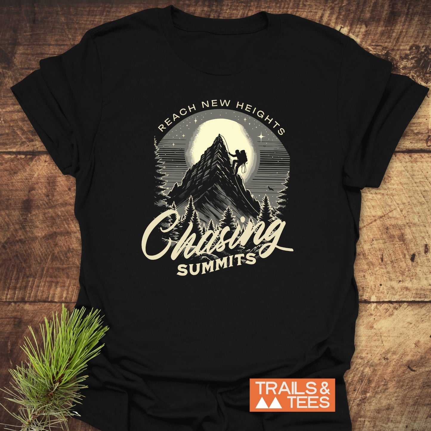 Black Chasing Summits T-shirt with vintage graphic of climber on mountain, full moon, and pine trees. Includes REACH NEW HEIGHTS text. Styled with evergreen.