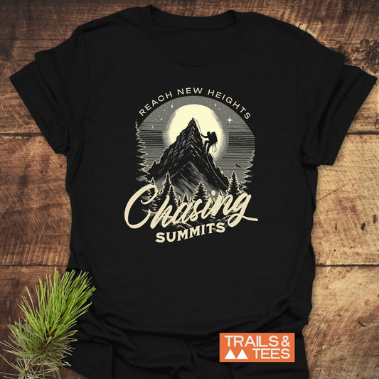 Black Chasing Summits T-shirt with vintage graphic of climber on mountain, full moon, and pine trees. Includes REACH NEW HEIGHTS text. Styled with evergreen.