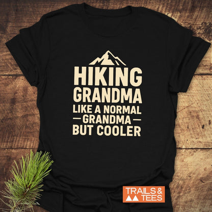 Hiking Grandma T-Shirt with mountain silhouette and slogan, featuring an orange Trails & Tees logo. Soft, lightweight cotton for everyday outdoor comfort.