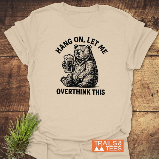 Light-tan Hang On Funny T-Shirt with a seated bear graphic and caption, crafted from soft cotton for comfort and durability. Perfect for outdoor enthusiasts.