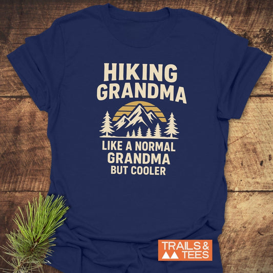 Navy blue Hiking Grandma Sunrise T-Shirt with mountain graphic and slogans, designed for comfort and durability, laid flat with pine sprig accent.