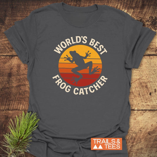 Frog Catcher T-Shirt featuring a retro sunset graphic and leaping frog, perfect for outdoor enthusiasts. Soft, durable, and pre-shrunk for a perfect fit.