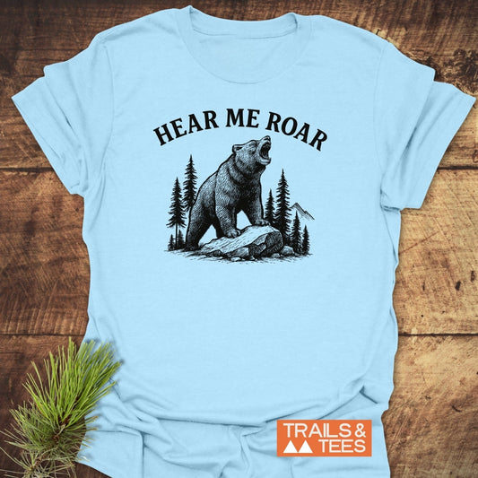 Hear Me Roar T-Shirt featuring a roaring bear illustration, framed by trees and mountains, with HEAR ME ROAR slogan. Includes TRAILS & TEES logo.