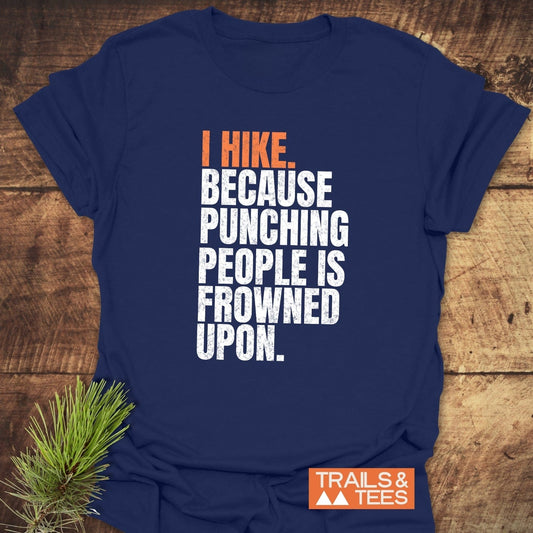 Navy-blue T-shirt with “I HIKE. BECAUSE PUNCHING PEOPLE IS FROWNED UPON.” text, featuring Trails & Tees logo; embodies outdoor adventure spirit.