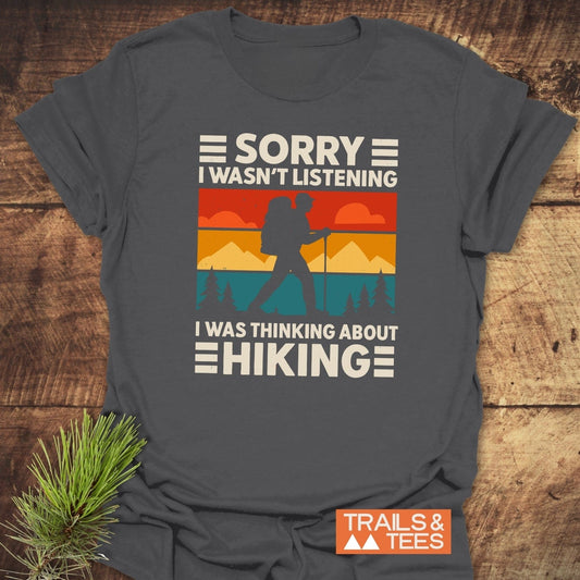 Thinking About Hiking T-Shirt featuring a retro graphic of a backpacker with mountain backdrop, crafted from soft ring-spun cotton for comfort and durability.