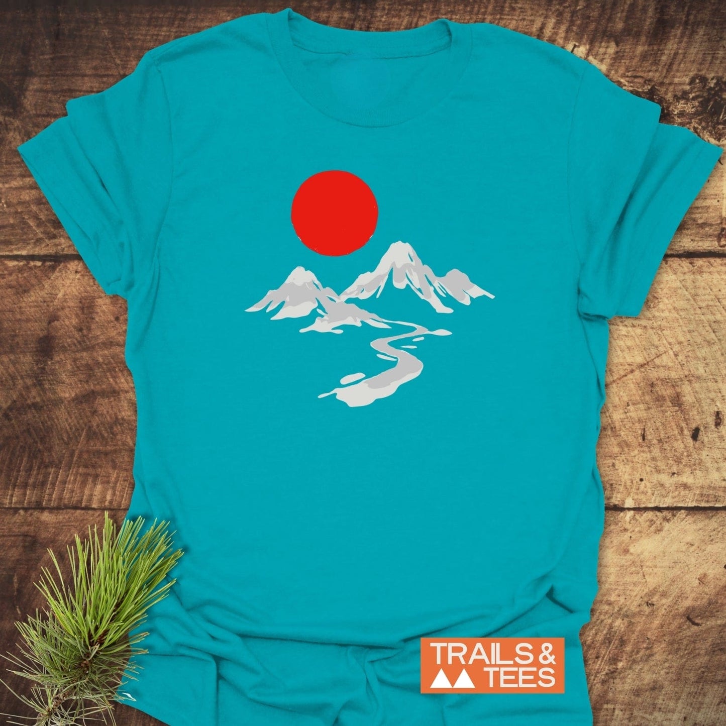 Crimson Sun T-Shirt featuring a minimalist mountain scene with red sun, crafted from soft, lightweight cotton for comfort and durability, labeled TRAILS & TEES.