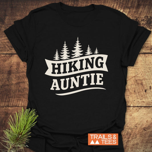 Hiking Auntie T-Shirt featuring evergreen tree graphic and “HIKING AUNTIE” text. Made from soft ring-spun cotton, perfect for outdoor enthusiasts.