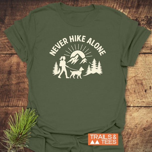 Never Hike Alone Dog Mom T-Shirt featuring an outdoor graphic with a person and dog, crafted from soft cotton, offering comfort and durability.