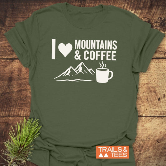 Olive-green T-shirt with “I ♥ MOUNTAINS & COFFEE” graphic, showcasing mountain peaks and a coffee mug, by TRAILS & TEES. Perfect for outdoor enthusiasts.