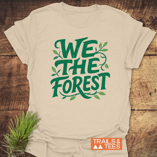 We The Forest T-Shirt with green vine print, laid on wood, features 'TRAILS & TEES' logo, crafted from soft ring-spun cotton, designed for outdoor enthusiasts.