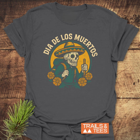 Dark-gray Hiking Skull T-Shirt featuring a skeleton with sombrero graphic, marigold accents, and “DÍA DE LOS MUERTOS” text, showcasing adventure-ready comfort and design.