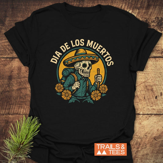Hiking Skull T-Shirt featuring a Dia de los Muertos skeleton with hiking gear, marigold flowers, and a halo; designed for comfort and adventure.