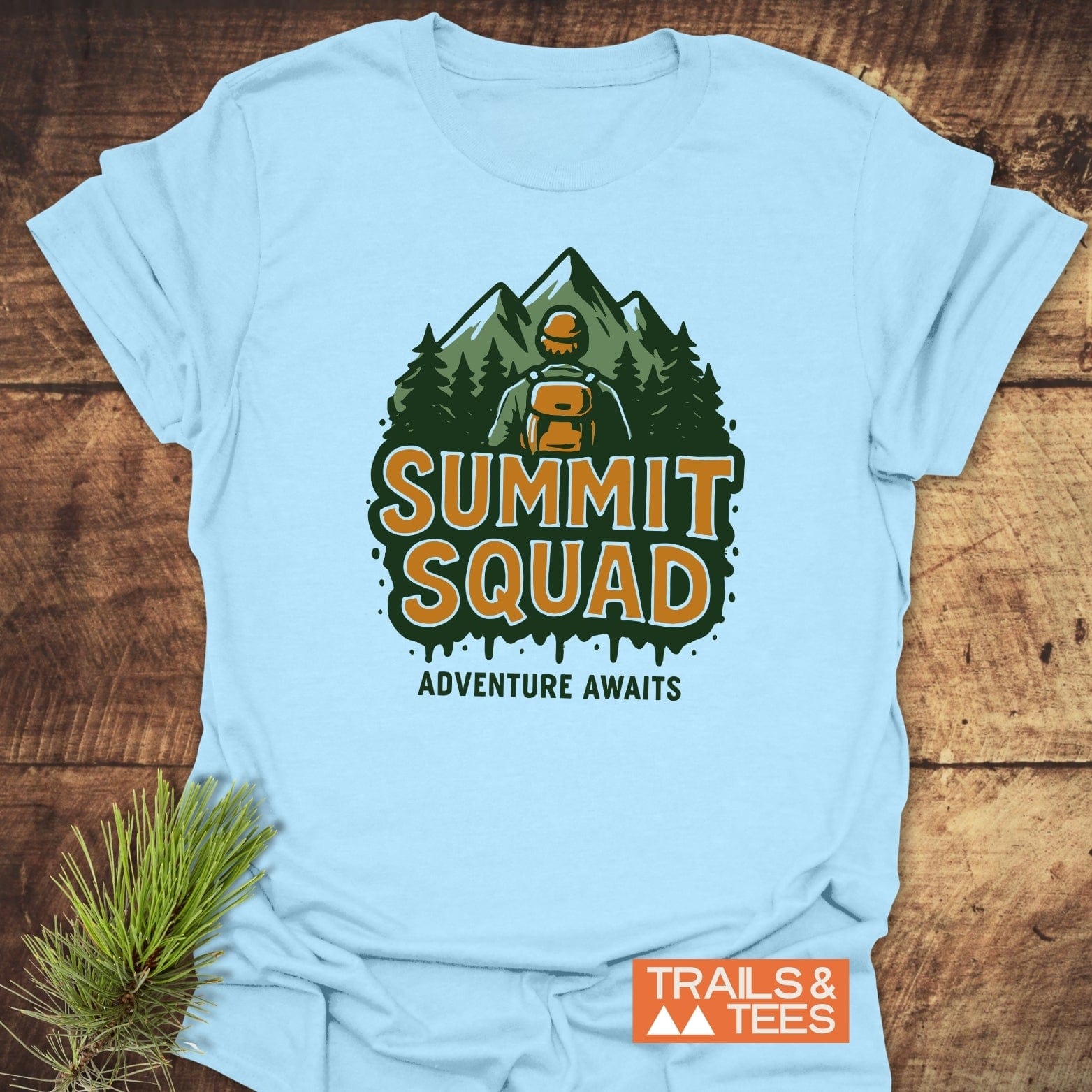 Summit Squad Hiking T-Shirt featuring a hiker graphic with “ADVENTURE AWAITS” text. Made from soft cotton, ensuring comfort and durability. Brand: TRAILS & TEES.