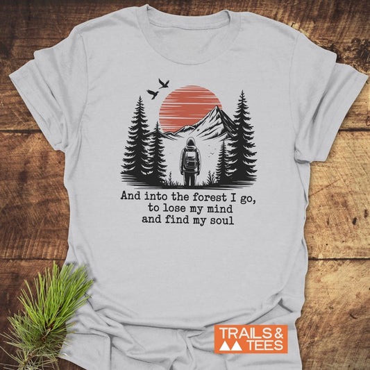 And Into The Forest I Go T-Shirt with nature graphic featuring sun, trees, hiker, and birds. Soft, lightweight cotton for everyday adventure. Durable, pre-shrunk, and eco-friendly.