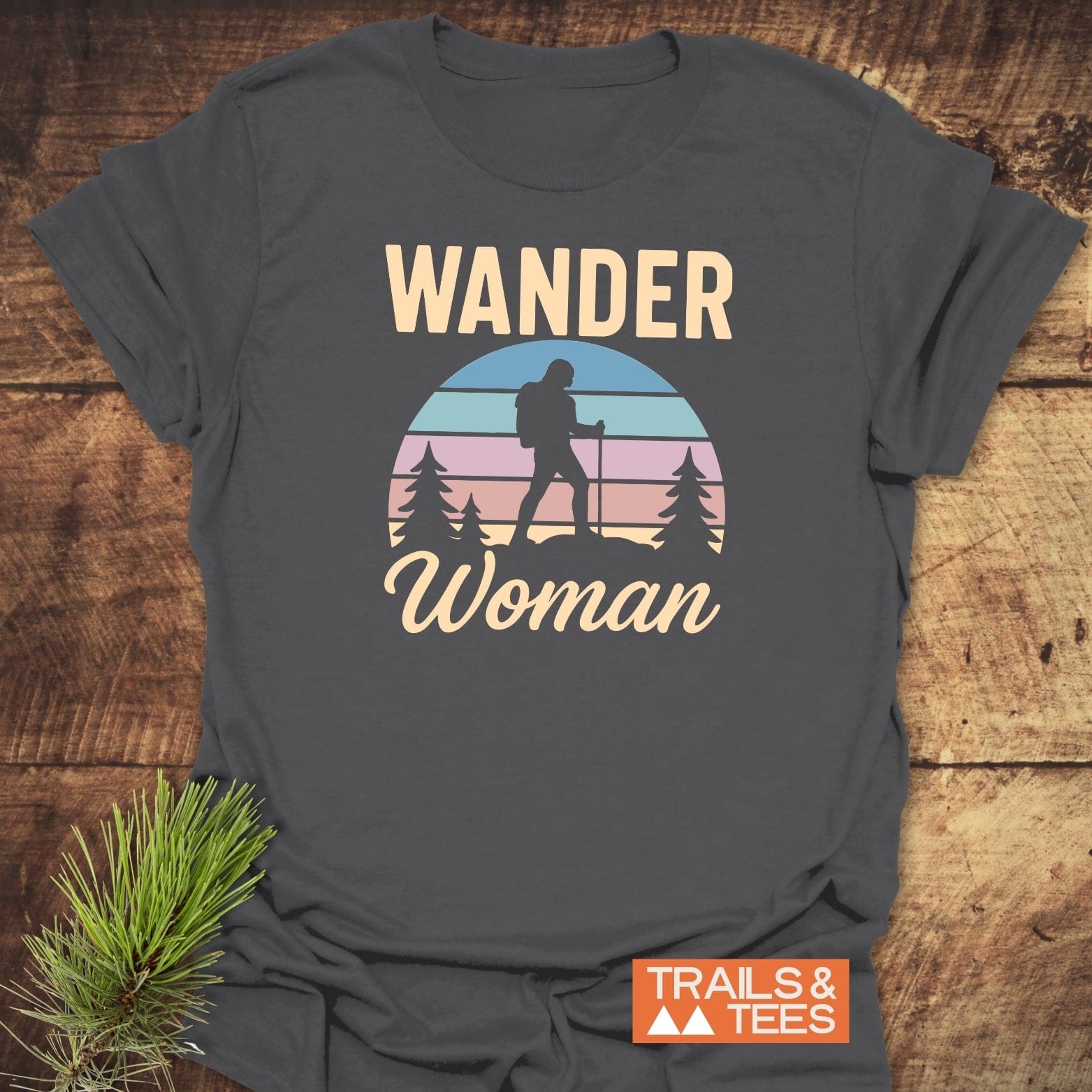 Wander Woman Retro T-Shirt featuring a hiker silhouette graphic with pastel sunset and pine trees, on soft, durable cotton for outdoor enthusiasts.