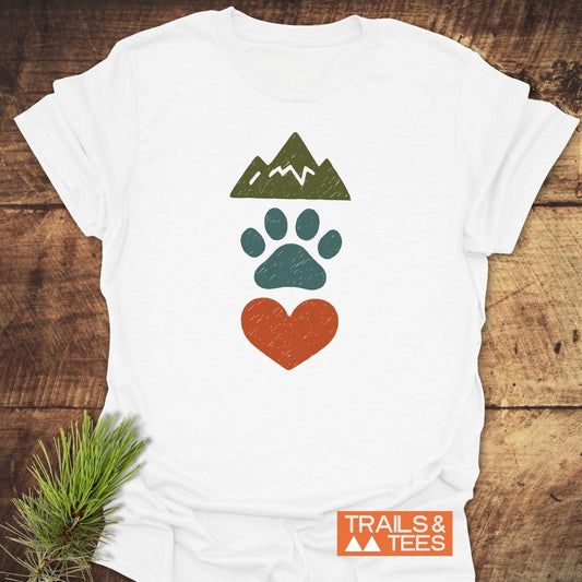 Mountains & Dogs Love T-Shirt featuring mountain, paw, and heart icons. Soft, durable, pre-shrunk cotton for outdoor enthusiasts. Overlapping TRAILS & TEES logo.